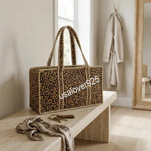 May include: A rectangular tote bag featuring a brown and black leopard print pattern with light-colored trim and two top handles. The text usalover925 is printed across the front of the bag. The bag has a structured shape with visible piping.
