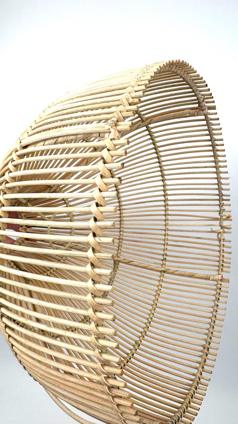 May include: A natural-toned, woven rattan lampshade with a rounded, open design. The shade features vertical and horizontal woven elements, creating a textured, airy appearance. The light brown color suggests a natural, eco-friendly aesthetic.