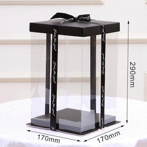 Puede incluir: Una caja de plástico transparente con tapa negra y cinta negra. La caja mide 17 cm de ancho, 17 cm de largo y 29 cm de alto. La caja tiene el texto "Just for you" impreso en la cinta.
