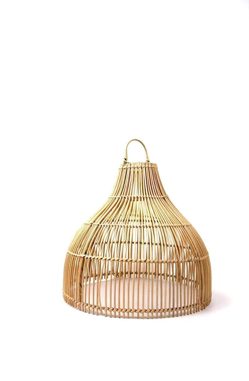 May include: A natural woven rattan lampshade with a bell shape and a handle at the top. The lampshade is made of vertical and horizontal rattan strips, creating an open, airy design. The color is a light tan.