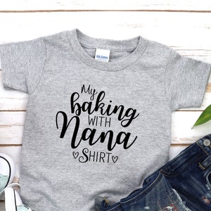 May include: A grey short-sleeved t-shirt with the text "My baking with Nana Shirt" printed in black.