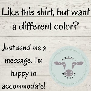 May include: Text on a woodgrain background that reads "Like this shirt, but want a different color? Just send me a message. I'm happy to accommodate!" with a cow logo that says "M3 Farm Boutique" in a circle.