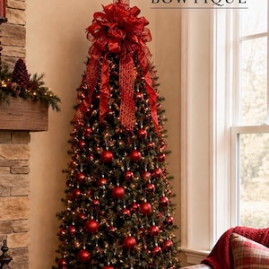 May include: A tall, slender Christmas tree decorated with numerous shiny red spherical ornaments and warm white string lights. A large, multi-layered red ribbon bow with a textured mesh pattern sits at the very top. Text reads Lakehouse BOWTIQUE.