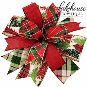 May include: A decorative bow featuring a mix of red, green, and white ribbons with plaid patterns and pine tree prints. The edges are trimmed with gold wire. The text Lakehouse BOWTIQUE is printed in black in the upper right corner.