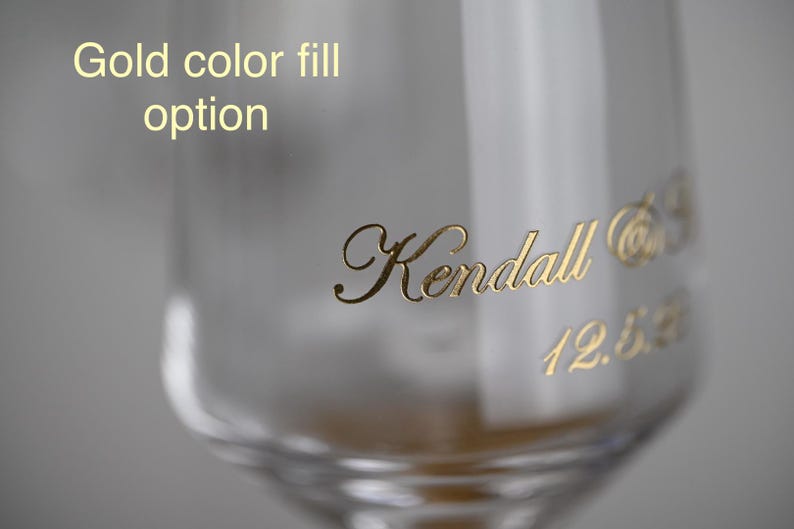 Puede incluir: Primer plano de un vaso transparente con letras doradas. El texto dice "Kendall" en cursiva, junto con texto dorado adicional y la fecha "12.5.62". Las palabras "Gold color fill option" est&aacute;n en la parte superior.