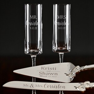 May include: A wedding cake serving set with two champagne flutes and a cake knife. The flutes are engraved with "MR. Corristo 3.12.22" and "MRS. Corristo 3.12.22". The cake knife is engraved with "Kristi and Shawn March 12, 2022" and "Mr. & Mrs. Corriston".