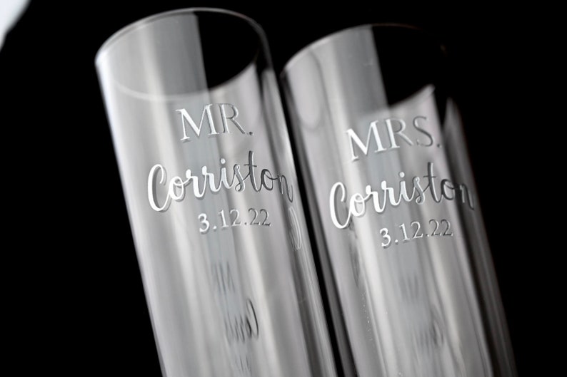 May include: Two clear glass champagne flutes with the text "MR. Corriston 3.12.22" and "MRS. Corriston 3.12.22" etched on them.