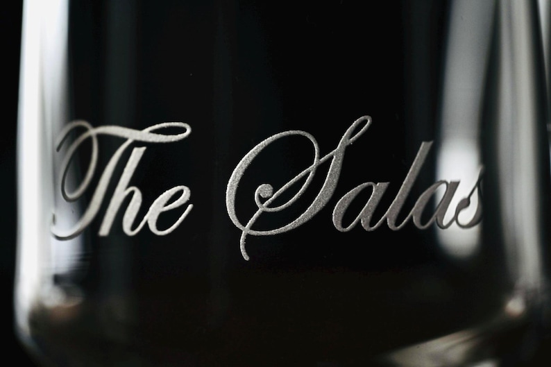 Puede incluir: Primer plano de un vaso con las palabras "The Salas" grabadas en una elegante escritura plateada. El texto est&aacute; centrado sobre un fondo oscuro, con los bordes del vaso visibles.