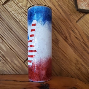 May include: A red, white, and blue glitter tumbler with a peace sign design. The tumbler is made of stainless steel and has a double-walled construction to keep drinks cold or hot for hours.