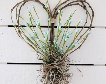 Rustic farmhouse springtime twig heart wall decor with pastel blue floral “hearts”.