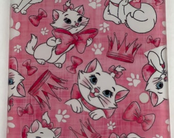 May include: A pink and white glass coaster with a repeating pattern of white kittens wearing pink bows and crowns. The background is a pink and white plaid pattern.