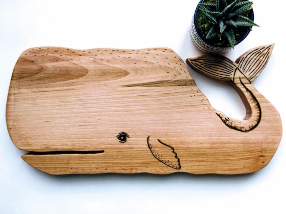 A hand-carved whale silhouette cutting board that doubles as genuine wall-worthy ocean art — functional craft with a strong visual identity.