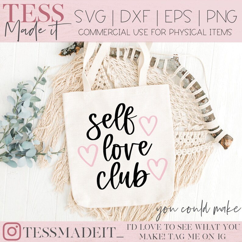 May include: A white tote bag with the text "Self love club" in black cursive lettering and pink hearts. The text "You could make" is written in black cursive lettering below the main text. The tote bag is on a white wooden surface with a macrame wall hanging in the background.
