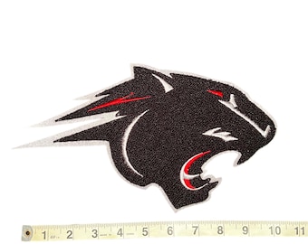 May include: A black panther head patch with red accents on the eyes and mouth. The patch has a textured surface and a white outline. A measuring tape is placed below the patch, showing a length of approximately 10 inches.