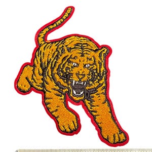 May include: Embroidered tiger patch in shades of gold and black, outlined in red. The tiger is depicted in a running pose with an open mouth, showcasing its teeth. The patch is approximately 5 inches in length.