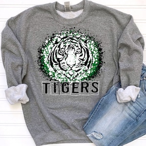 May include: Gray sweatshirt with a green and white splatter design featuring a white tiger head and the word "TIGERS" in black.