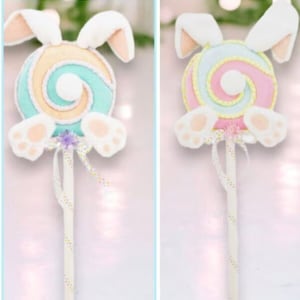 May include: Two pastel-colored bunny lollipop decorations. Each lollipop has a white bunny head with ears and feet, and a swirl lollipop with pink, blue, and yellow colors.