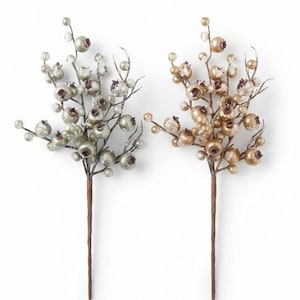 May include: Two decorative floral stems featuring round berries with a textured, glittery finish. One stem displays light sage green berries, while the other features metallic gold berries. Both stems have brown wrapped wire stalks.
