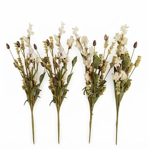 Könnte beinhalten: Vier künstliche Blumenstiele mit cremefarbenen Blüten, grünem Blattwerk und kleinen braunen Samenkapseln. Jeder Stiel ist mit einer Mischung aus zarten Blütenblättern und strukturiertem Grün arrangiert, was ein stimmiges botanisches Arrangement ergibt.