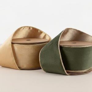 May include: Two spools of wide ribbon, one in a metallic gold finish and the other in a deep forest green velvet texture. Both spools feature a matching metallic gold wired edge, providing structure to the fabric as it loops around the center.