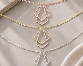 May include: Three necklaces with delicate link chains, each featuring a geometric pendant composed of two nested, angular diamond-shaped frames. The pendants are finished in rose gold, yellow gold, and silver tones, with a single small clear stone.
