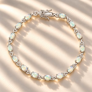 May include: A silver-toned bracelet featuring a series of oval-shaped iridescent opals alternating with small round clear stones. The links are connected by a delicate metal pattern, and the piece is secured with a rectangular box clasp.