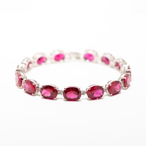 Puede incluir: Un brazalete de plata con una fila de piedras ovaladas de color rosa brillante.