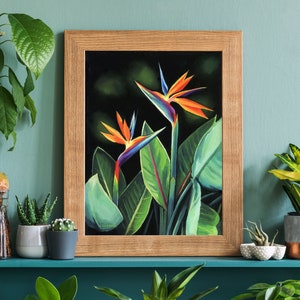 Puede incluir: Una pintura enmarcada de dos flores de ave del para&iacute;so naranja y azul sobre un fondo verde oscuro. La pintura est&aacute; en un estante con varias plantas en macetas.
