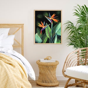 Puede incluir: Una impresi&oacute;n enmarcada de una pintura con dos flores de ave del para&iacute;so vibrantes de color naranja, azul y verde sobre un fondo verde oscuro.