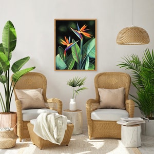 Puede incluir: Dos flores de ave del para&iacute;so en una pintura enmarcada, con dos sillas de mimbre y plantas en macetas en un sal&oacute;n.