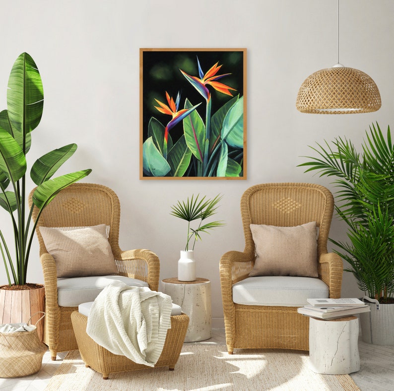Puede incluir: Dos flores de ave del para&iacute;so en una pintura enmarcada, con dos sillas de mimbre y plantas en macetas en un sal&oacute;n.