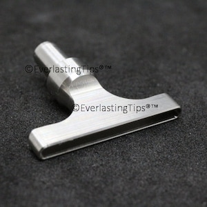 May include: A silver metal T-shaped tool with a rounded handle. The tool has a flat, rectangular blade with a groove running along the center. The text "©EverlastingTips®TM" is printed on the handle and blade.