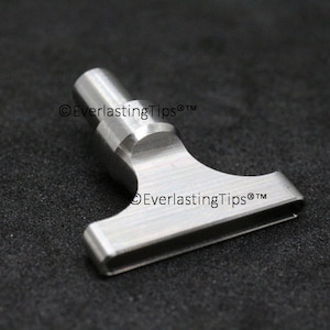 May include: A silver metal tool with a T-shaped head and a cylindrical handle. The tool is engraved with the text "EverlastingTips® TM".