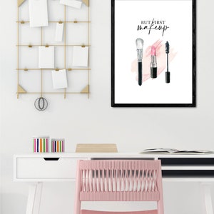 May include: A black framed print with the text "But first, makeup" in white. The print features a watercolor illustration of a makeup brush, lipstick, and mascara.