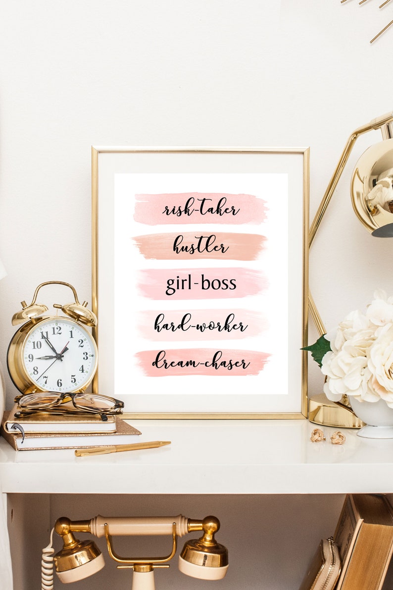 May include: A framed print with a white background and pink watercolor stripes. The text on the print reads "risk-taker", "hustler", "girl-boss", "hard-worker", and "dream-chaser".