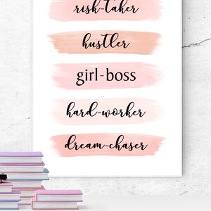 May include: A white poster with pink watercolor brushstrokes and the words "risk-taker", "hustler", "girl-boss", "hard-worker", and "dream-chaser" written in black cursive.