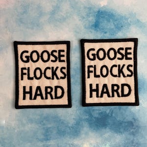 May include: Two white fabric patches with black embroidered text. The text on both patches reads "Goose flocks hard".