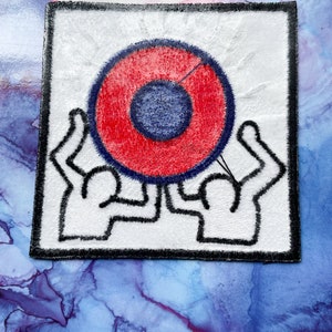 May include: A white patch with a black border features a red and blue circle with two stylized figures holding it up.