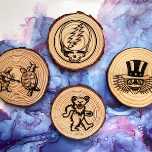 May include: Four wooden coasters with different designs. The coasters feature a skull with lightning bolt, a bear, two turtles, and a skull with a top hat and sunglasses.