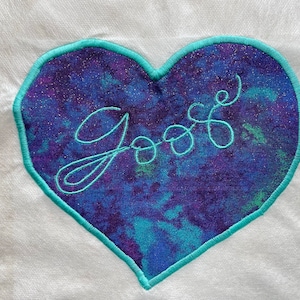 May include: A blue and purple heart-shaped patch with a teal outline and the word "Goose" embroidered in teal.
