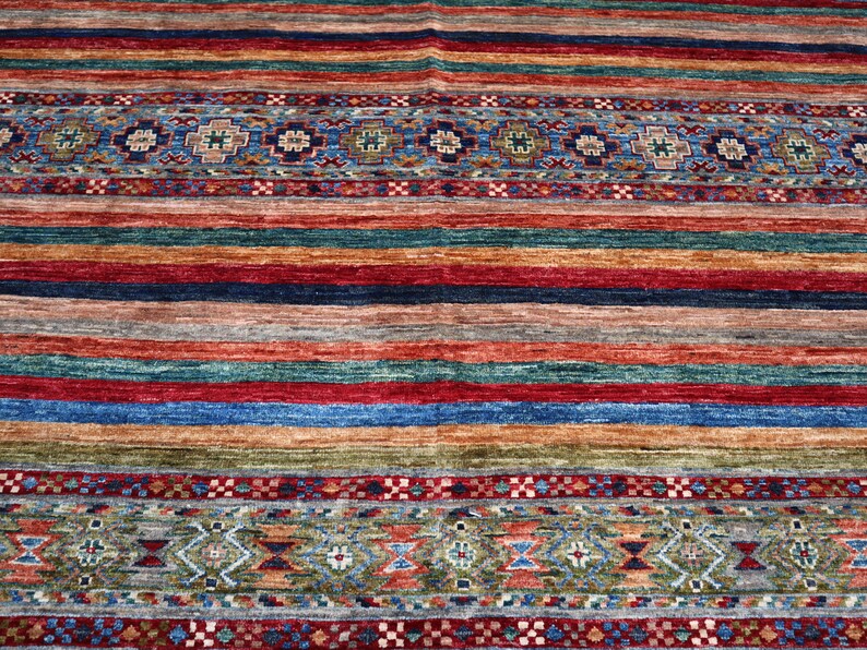 May include: A colorful rug with a striped pattern and intricate border designs. The rug features a variety of colors, including red, blue, green, and brown.