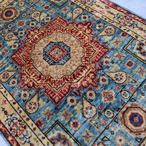 May include: A detailed, rectangular rug with a central medallion design. The rug features a vibrant color palette of teal, red, beige, and gold. Intricate patterns and borders add to the rug's traditional aesthetic. The rug is suitable for home decor.