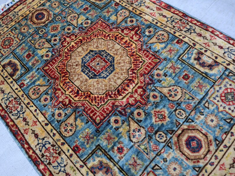May include: A detailed, rectangular rug with a central medallion design. The rug features a vibrant color palette of teal, red, beige, and gold. Intricate patterns and borders add to the rug's traditional aesthetic. The rug is suitable for home decor.