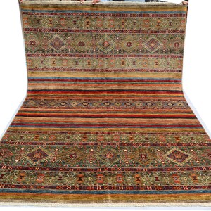 May include: A colorful rug with a geometric pattern in shades of red, orange, yellow, green, blue, and brown. The rug has a fringe border.