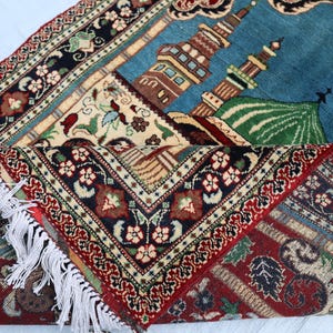 May include: A traditional prayer rug with intricate floral patterns in shades of red, blue, and green. The rug features a mosque design with a dome and minarets.
