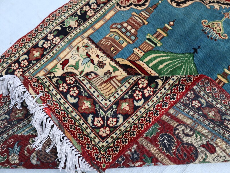 May include: A traditional prayer rug with intricate floral patterns in shades of red, blue, and green. The rug features a mosque design with a dome and minarets.
