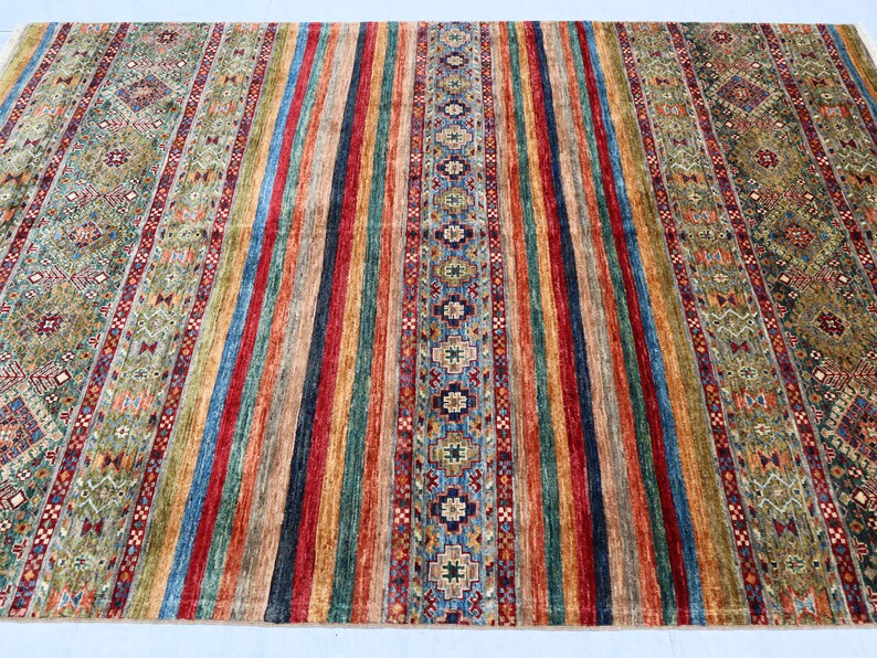 May include: A colorful rug with a striped pattern and intricate designs. The rug features a variety of colors, including red, blue, green, and yellow.
