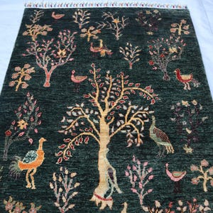 May include: A green rug with a repeating pattern of trees, birds, and flowers. The rug has a fringed edge.