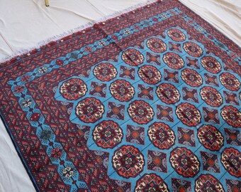 May include: A blue and red patterned rug with intricate designs. The rug has a geometric pattern with a central medallion.