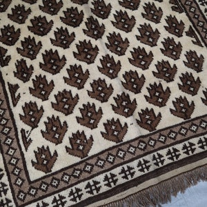May include: A brown and white patterned rug with a geometric design. The rug has a fringe border.